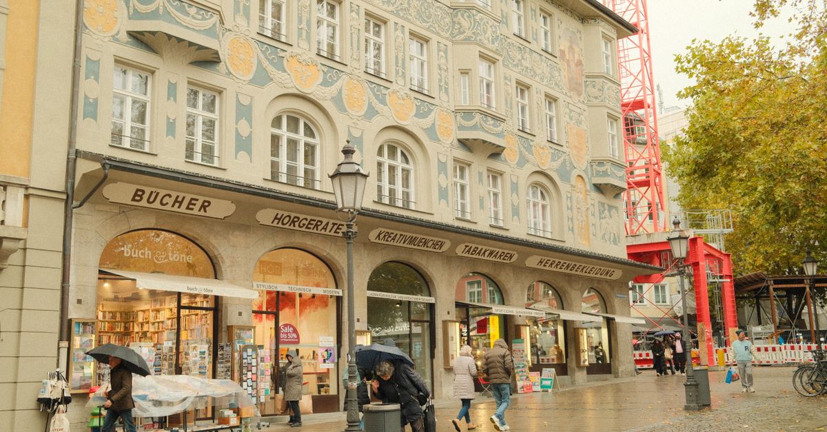 Passanten mit Regenschirmen an einem verregneten Tag vor historischer Architektur in München