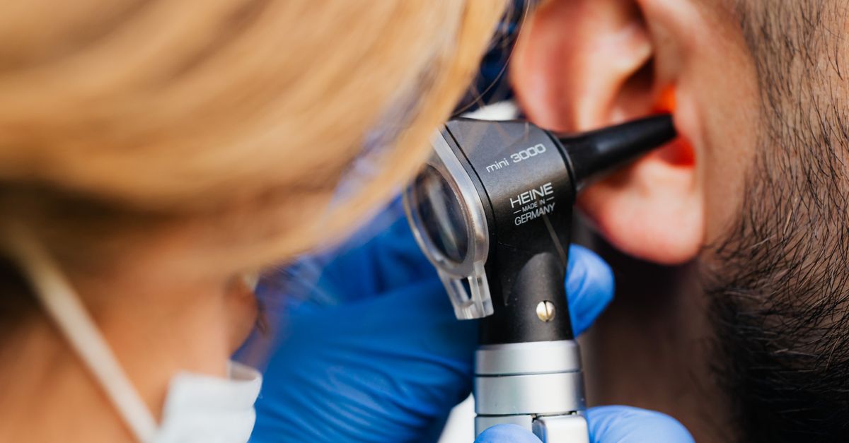 Medizinische Fachkraft untersucht das Ohr eines Patienten mit einem Heine-Otoskop